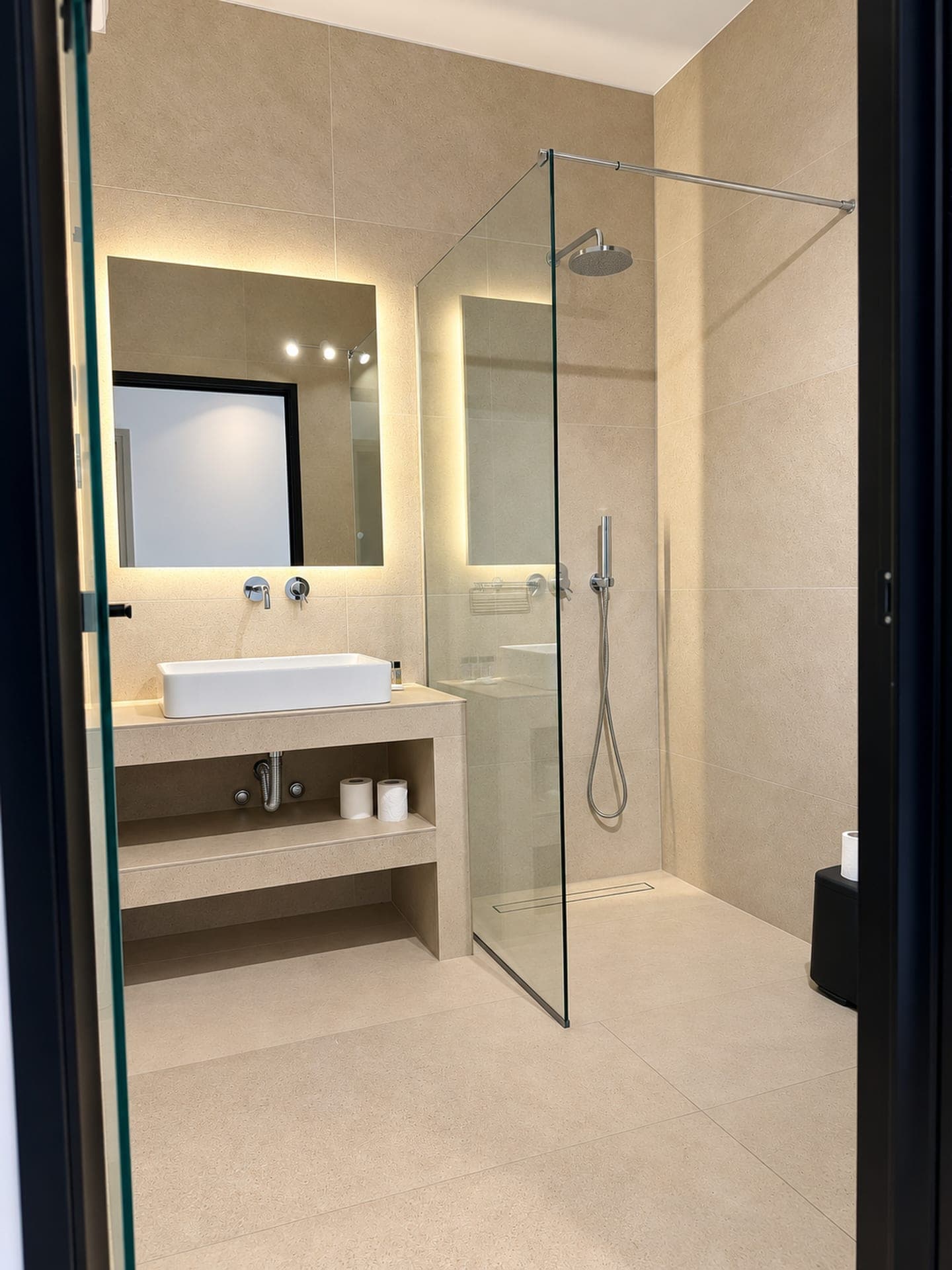 Bathroom with walk-in shower, vessel sink and backlit mirror